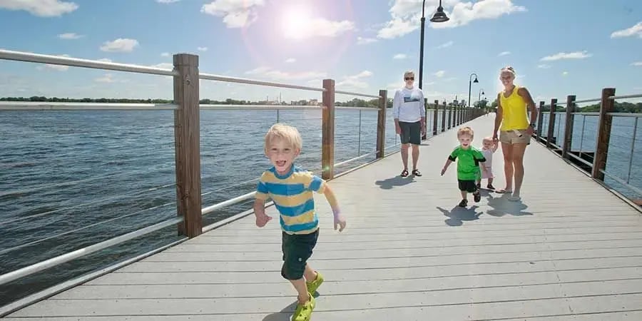 A family with young children enjoying a sunny walk on a scenic Fox River pier in Appleton, Wisconsin.
