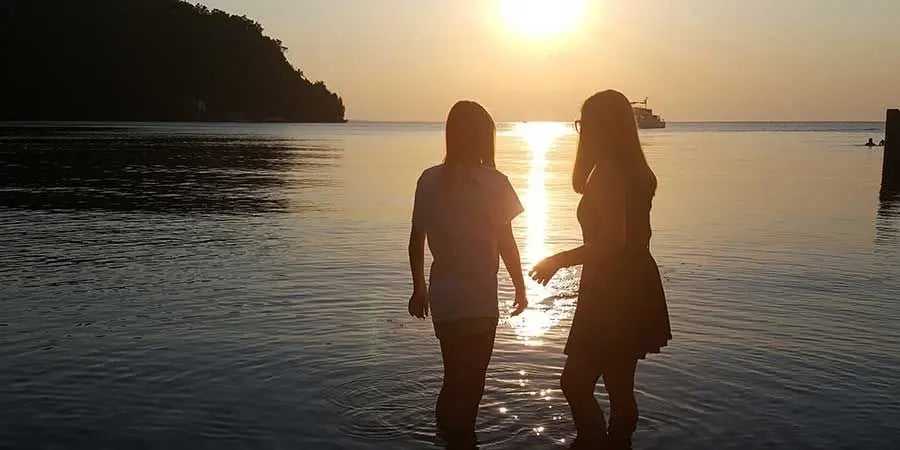 Silhouette of two friends standing in the water during a golden sunset at Green Bay, Wisconsin.