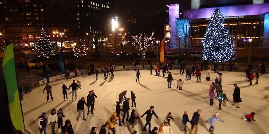 People ice skating on an outdoor rink in downtown Milwaukee, Wisconsin, next to a lit-up Christmas tree.