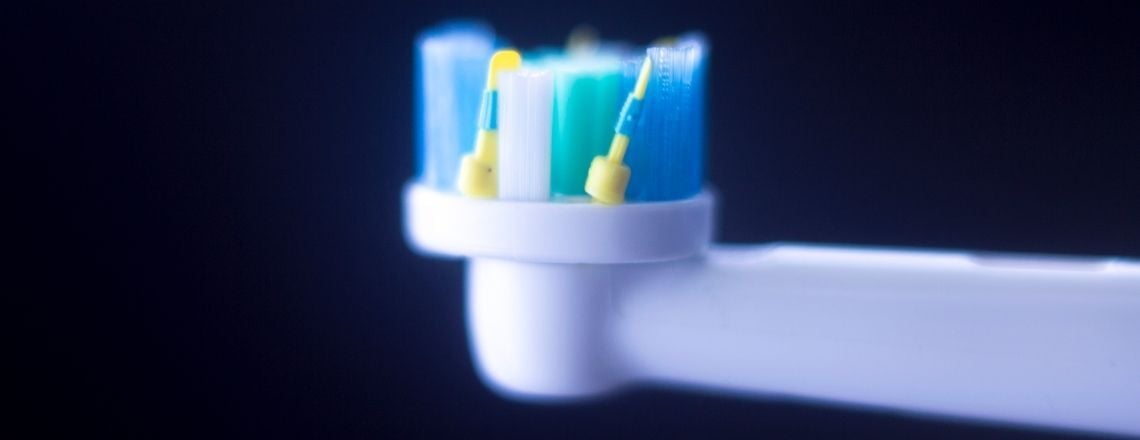 white and blue electric toothbrush on a dark background