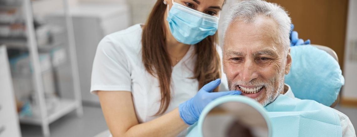 older man with a dental assistant getting an examination of his teeth