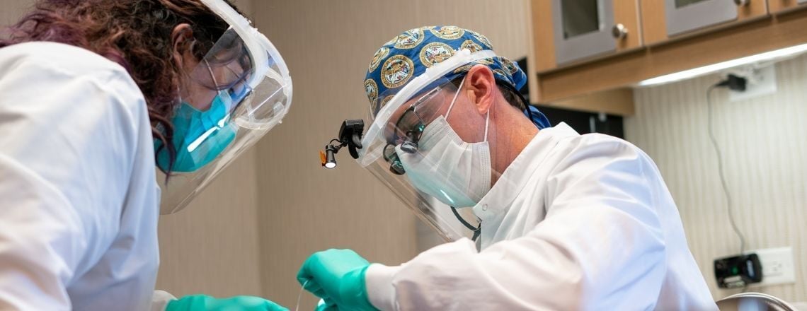 dentist wearing protective gear examining a patient
