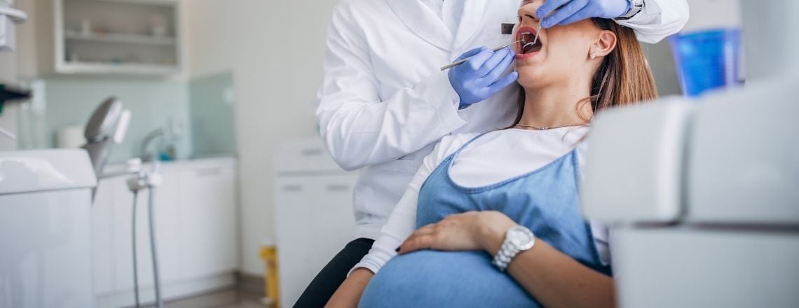 pregnant woman in a dental chair being examined by a dentist