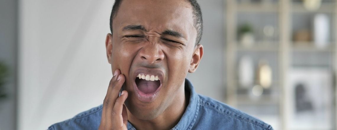 A man holds his jaw in pain, suffering from a severe toothache