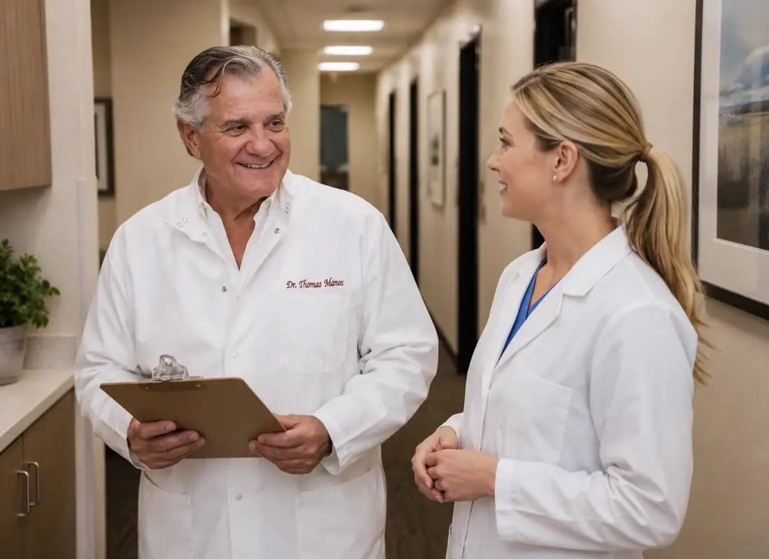 Dr. Thomas Manos discussing patient care with a female colleague in a clinic hallway.