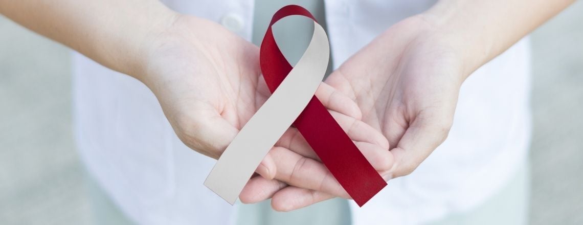 hands holding ribbon symbolizing oral cancer