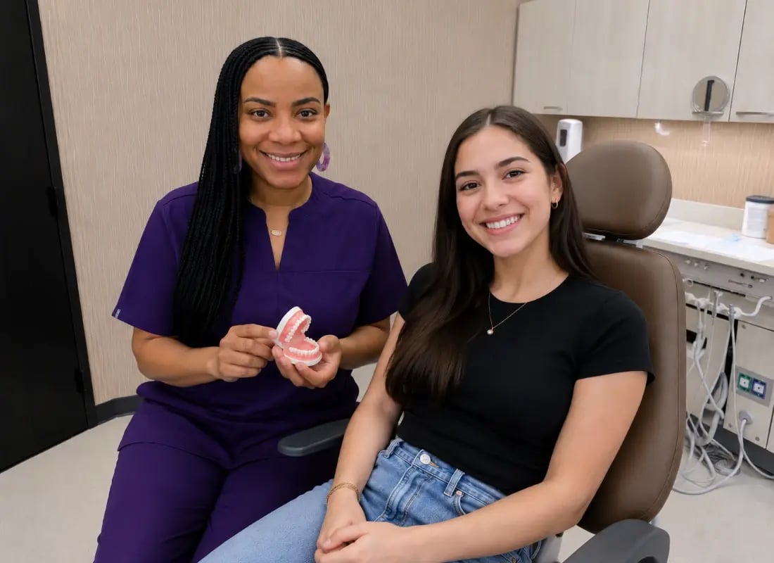 An oral surgery professional showing a jaw model to a smiling patient in a dental chair.