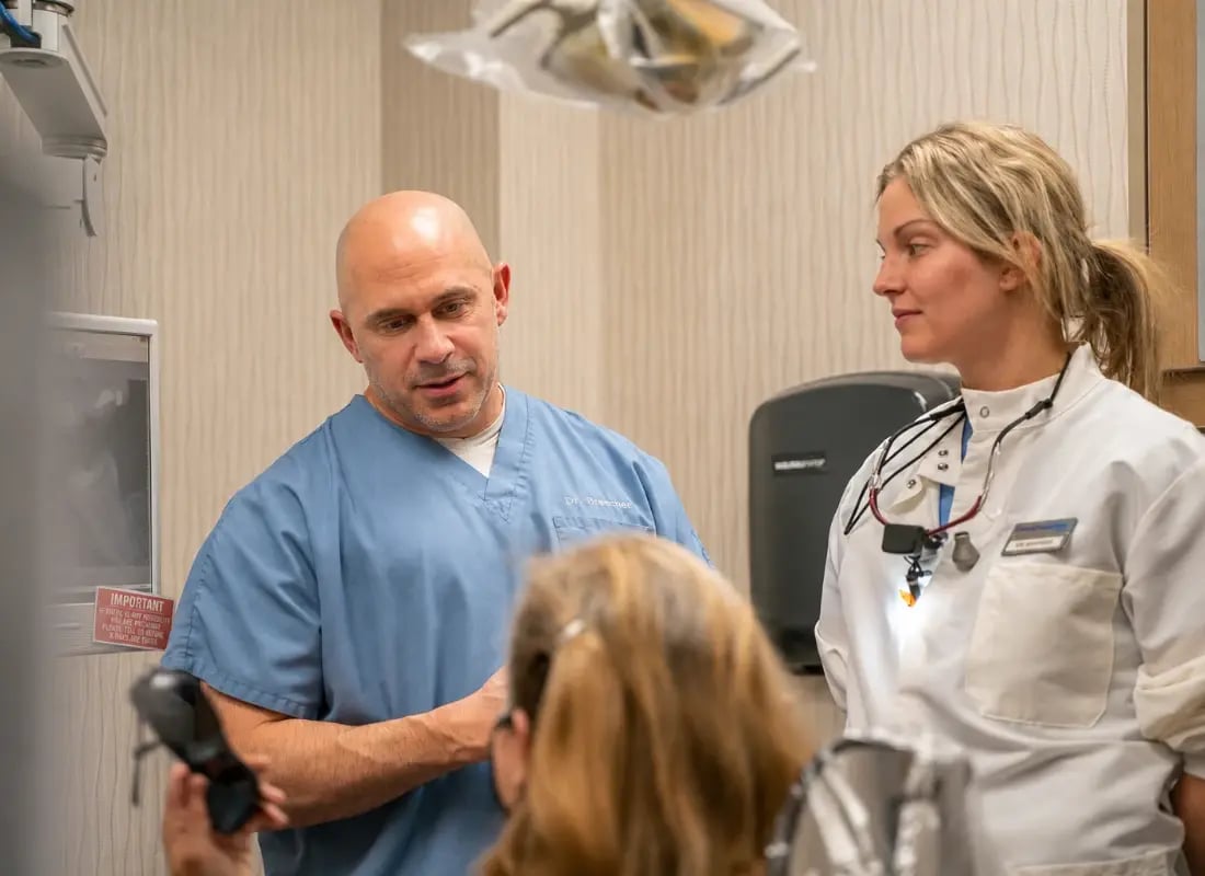 An endodontist and dental assistant discussing a patient treatment plan in a modern dental clinic.
