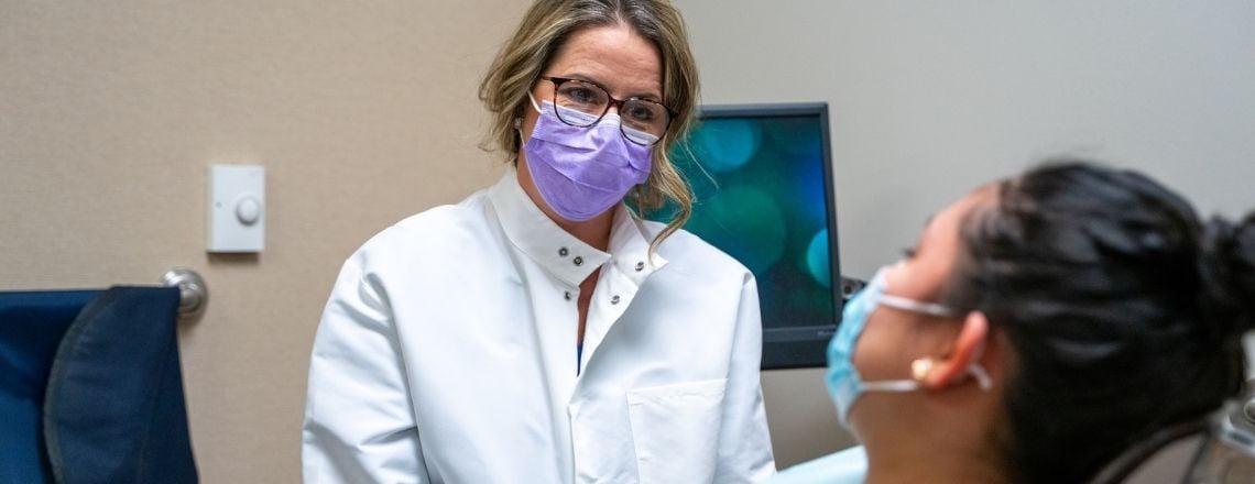 dental assistant wearing a mask talking to a patient in the dental chair