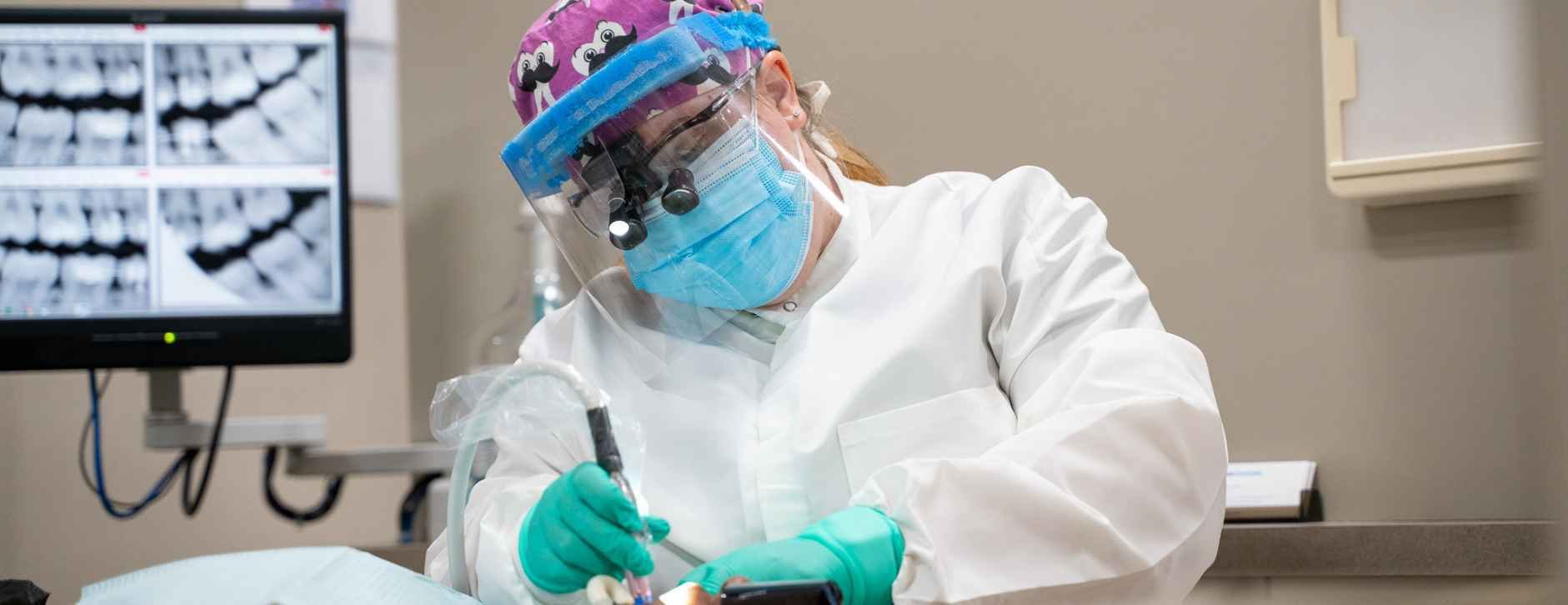 hygienist with dental loupe glasses on cleaning a patient's teeth
