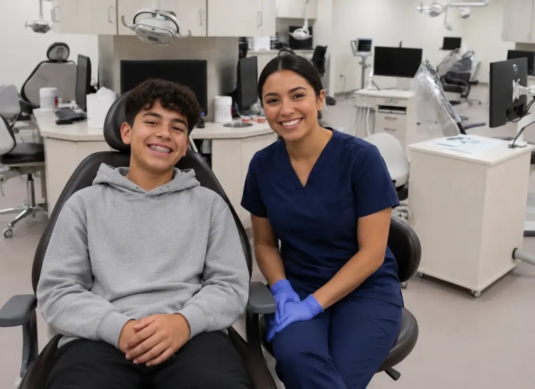 A teenage boy with braces smiles next to his female orthodontist in a modern dental clinic.
