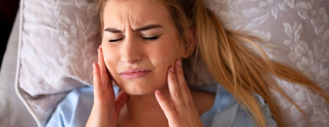 young woman holding her mouth in pain from teeth grinding