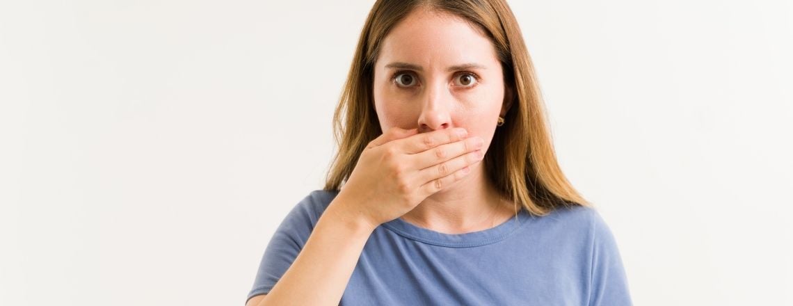 woman holding her mouth covering up her bad breath
