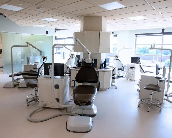 Modern open-concept dental clinic bay featuring multiple patient chairs and advanced examination equipment.