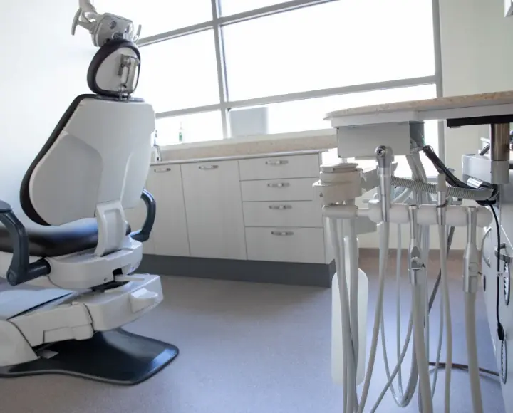 Modern dental clinic room featuring an ergonomic examination chair and professional dental instruments on a cart.