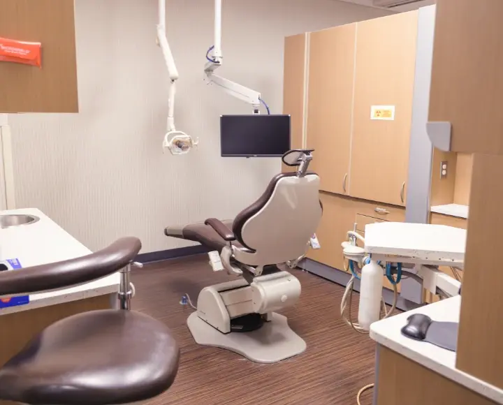 Clean and modern dental operatory room with a treatment chair, monitor, and clinical cabinets.