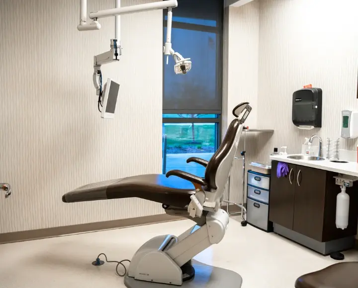 Modern dental exam chair and equipment in a clean dental clinic operatory room.