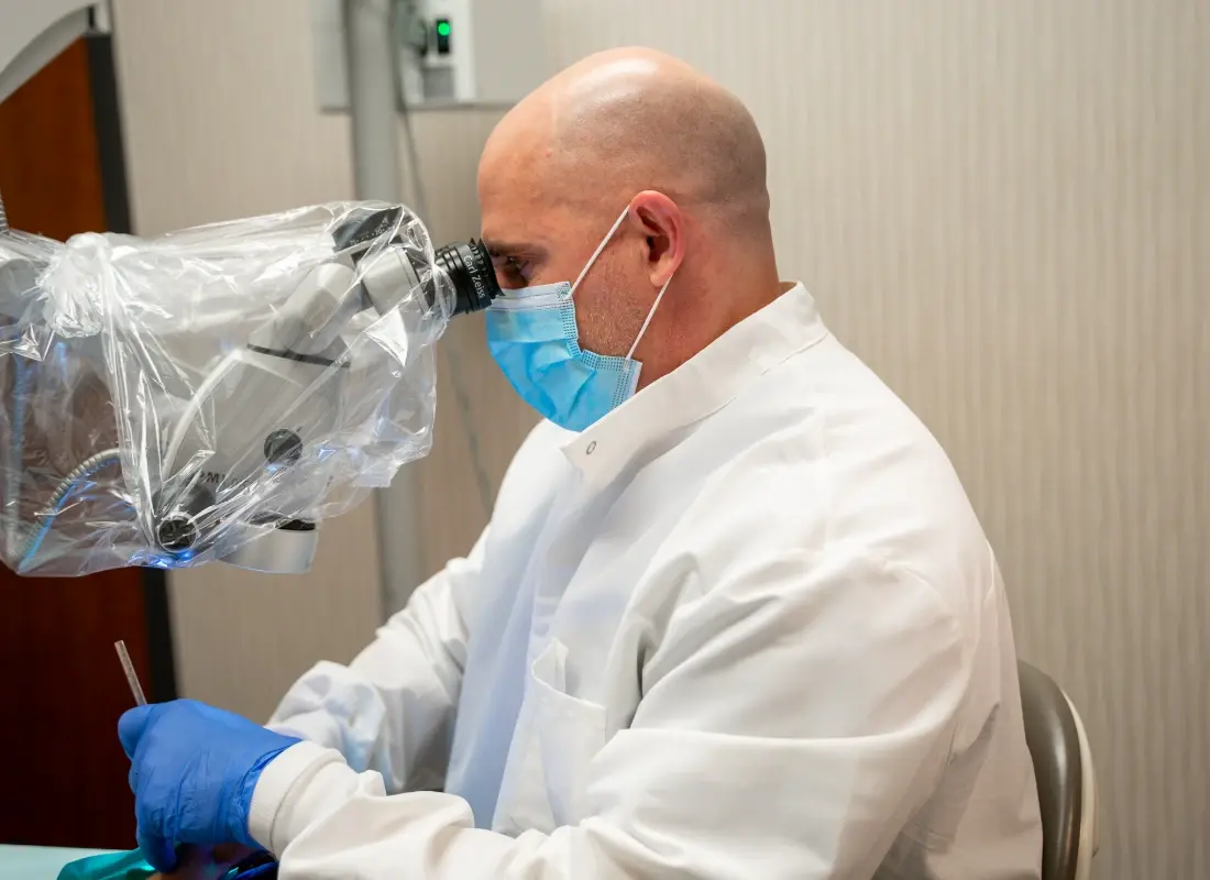 An endodontist using a specialized dental microscope during a clinical procedure.