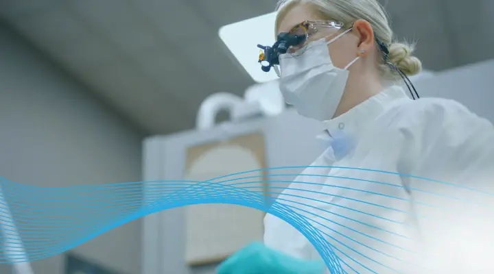 Female dental hygienist wearing a face mask and magnifying loupes at a clinic.